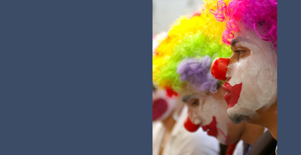 Two clowns in profile with brightly coloured wigs.